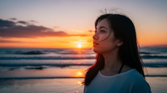 美しい夕暮れの海辺で、穏やかな表情で前を見つめる女性